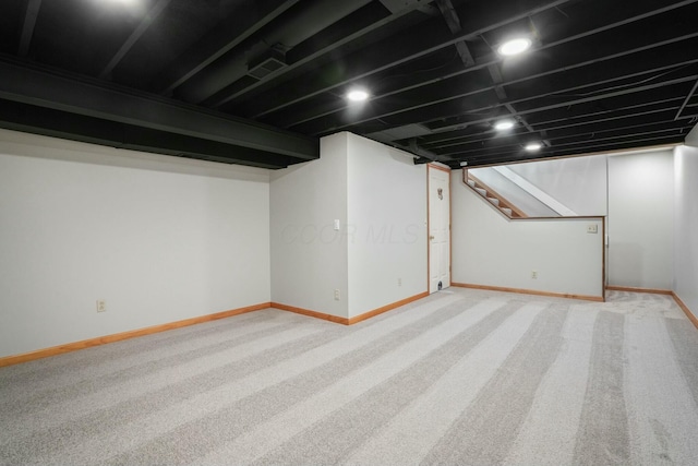 finished basement featuring light carpet, stairway, visible vents, and baseboards