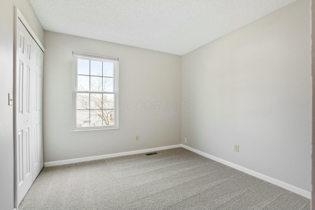 unfurnished bedroom with visible vents, baseboards, carpet floors, a closet, and a textured ceiling