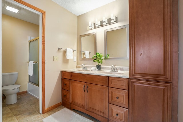 full bathroom featuring double vanity, toilet, baseboards, and a sink