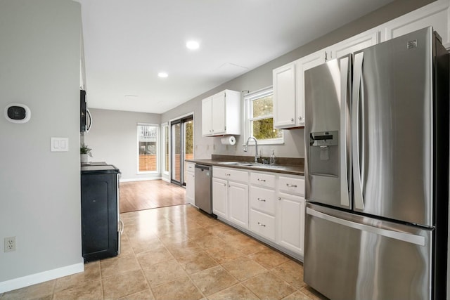 kitchen with a sink, dark countertops, white cabinets, and stainless steel appliances