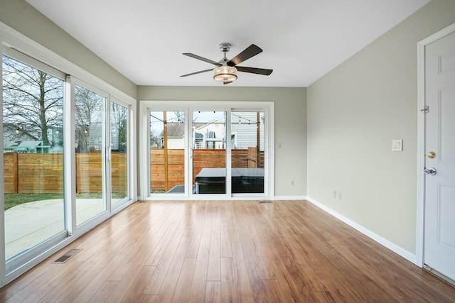 unfurnished sunroom featuring visible vents and a ceiling fan