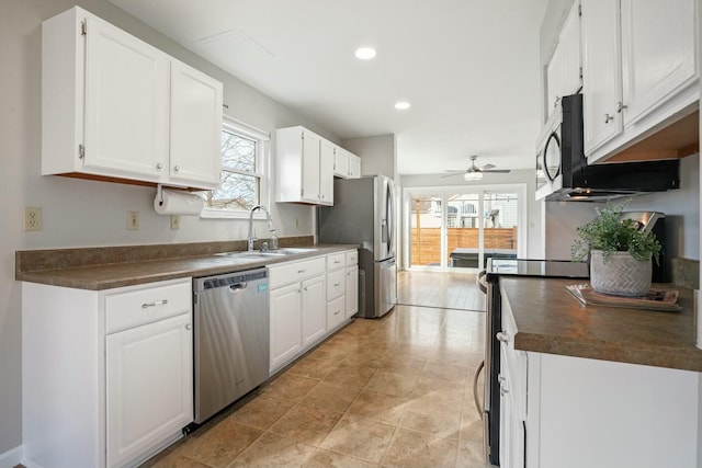 kitchen with dark countertops, appliances with stainless steel finishes, white cabinetry, and a sink