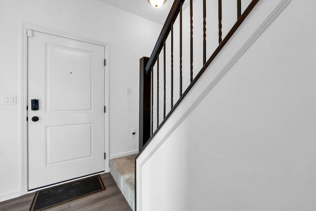 foyer entrance featuring baseboards, dark wood-type flooring, and stairs