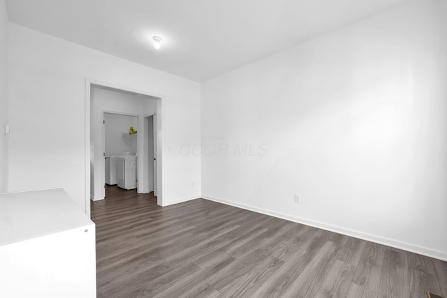 unfurnished room with dark wood-type flooring, baseboards, and washing machine and clothes dryer