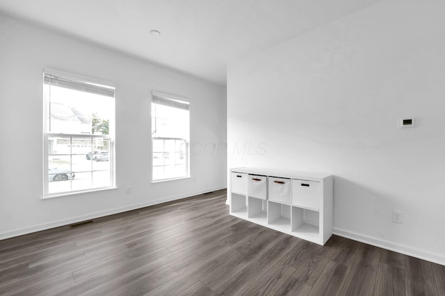 unfurnished room with dark wood-type flooring, baseboards, and visible vents