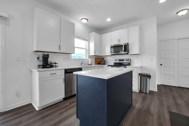 kitchen with stainless steel appliances, white cabinets, dark wood-style flooring, and light countertops