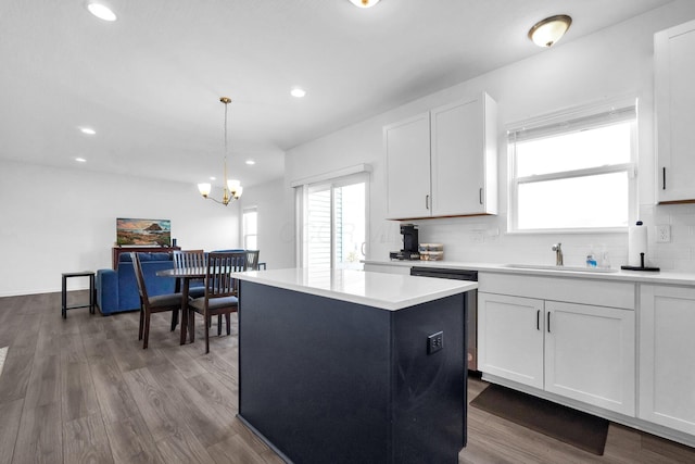 kitchen featuring a sink, backsplash, dark wood finished floors, a center island, and a healthy amount of sunlight