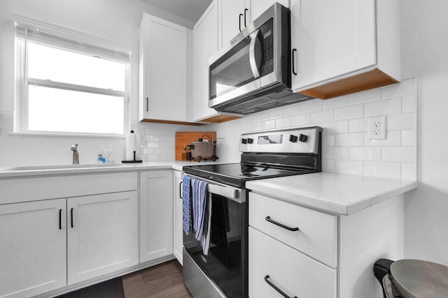 kitchen featuring backsplash, stainless steel appliances, dark wood-style floors, white cabinetry, and a sink