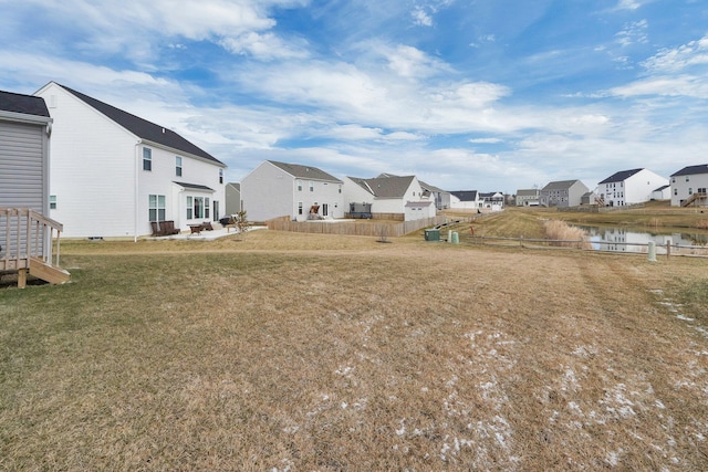 view of yard with fence, a residential view, and a water view