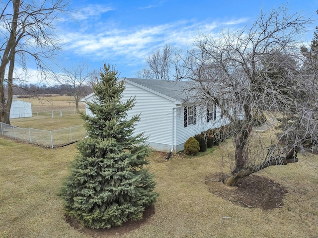 view of side of property featuring roof with shingles, a lawn, and fence