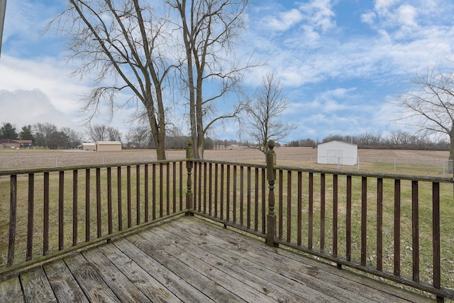 deck with an outbuilding, a rural view, a lawn, and a storage unit