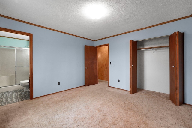 unfurnished bedroom with ensuite bath, crown molding, a textured ceiling, carpet floors, and a closet