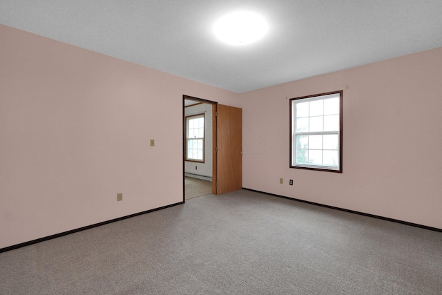 unfurnished room with light carpet and baseboards