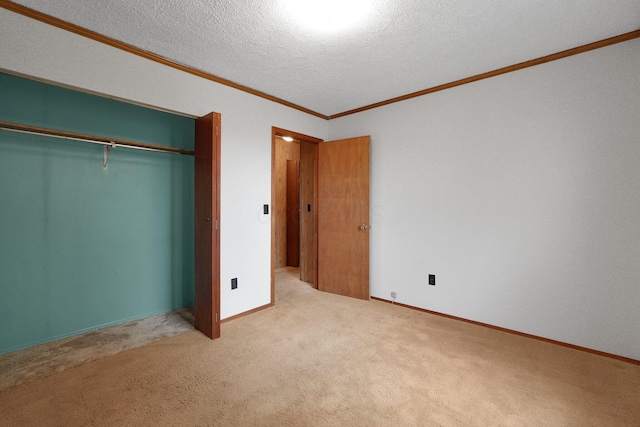 unfurnished bedroom with a closet, ornamental molding, carpet flooring, a textured ceiling, and baseboards