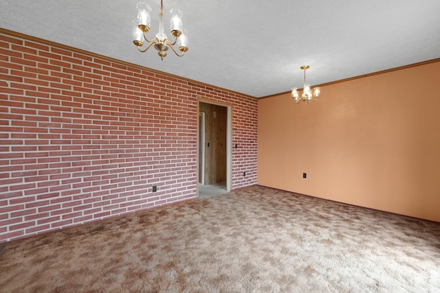 spare room featuring crown molding, brick wall, carpet, and an inviting chandelier