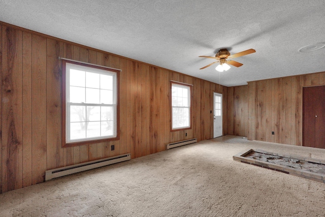 carpeted empty room with a textured ceiling, baseboard heating, and a wealth of natural light