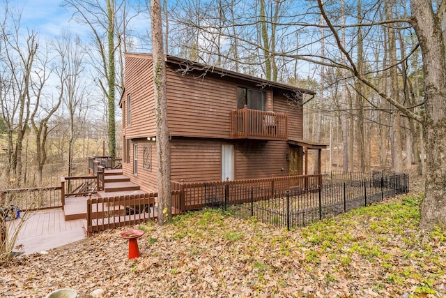 view of side of property with a deck, a balcony, and fence