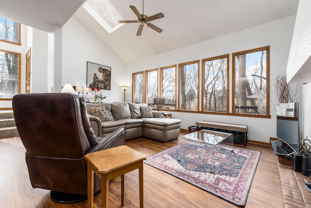 living area featuring high vaulted ceiling, a skylight, ceiling fan, and wood finished floors