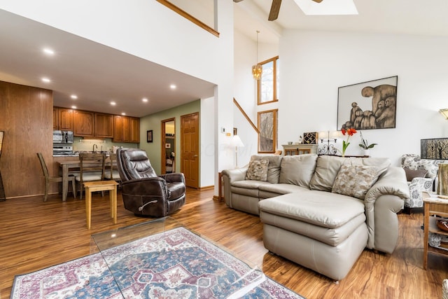 living area featuring a skylight, recessed lighting, wood finished floors, and high vaulted ceiling