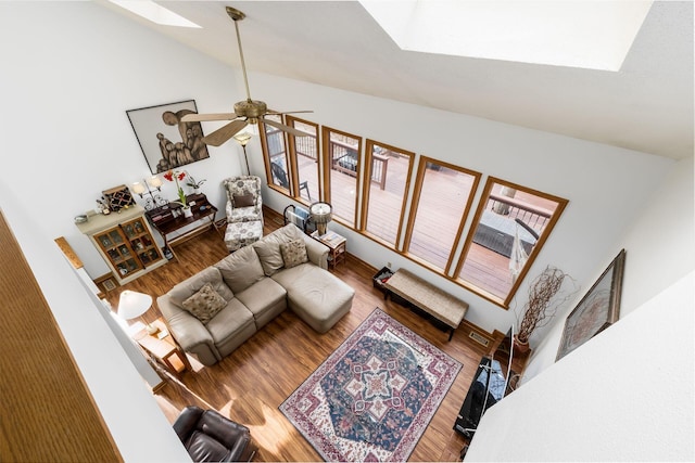 living room with visible vents, vaulted ceiling with skylight, wood finished floors, and a ceiling fan