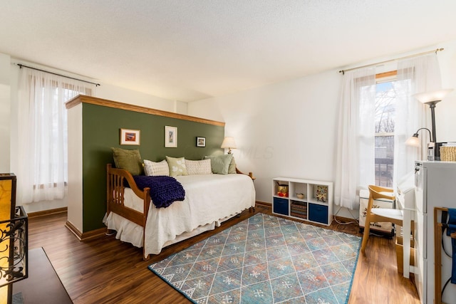 bedroom featuring baseboards, a textured ceiling, and wood finished floors