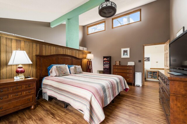 bedroom featuring beamed ceiling, wood finished floors, and a towering ceiling