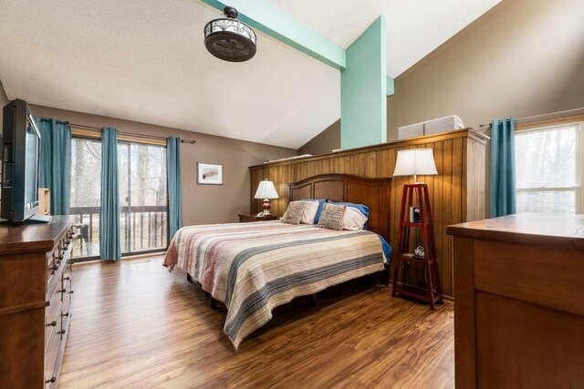 bedroom featuring access to outside, multiple windows, lofted ceiling, and wood finished floors