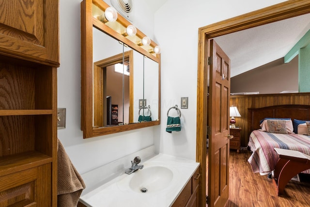 bathroom featuring vanity, lofted ceiling, and wood finished floors