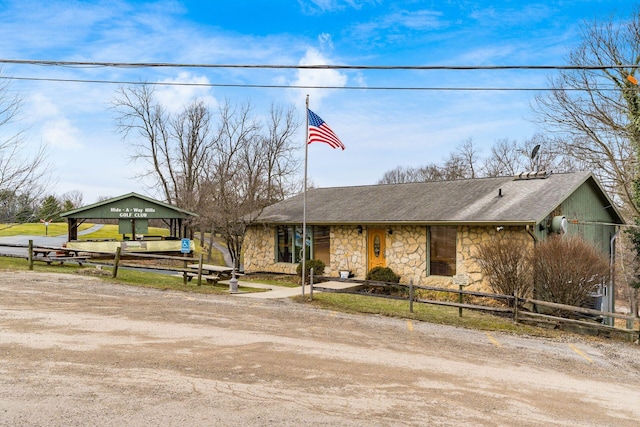 view of front of home featuring driveway, stone siding, and a fenced front yard