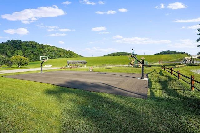 view of community featuring community basketball court, a yard, fence, and playground community