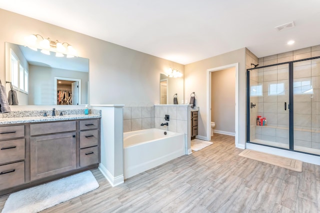 full bath featuring visible vents, a shower stall, toilet, a garden tub, and vanity