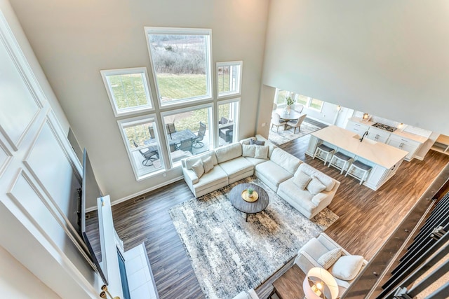 living room with baseboards, a high ceiling, and wood finished floors