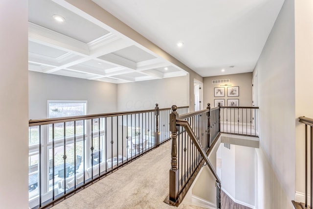 hallway with visible vents, an upstairs landing, beam ceiling, coffered ceiling, and carpet flooring