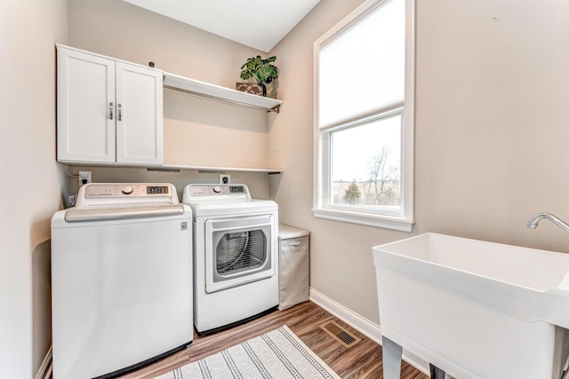 laundry room with independent washer and dryer, a sink, wood finished floors, cabinet space, and baseboards