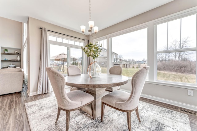 dining room with a wealth of natural light, a chandelier, baseboards, and wood finished floors