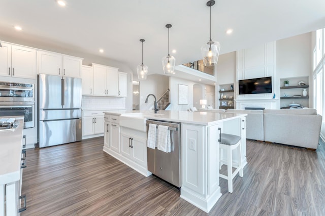 kitchen featuring a sink, tasteful backsplash, open floor plan, appliances with stainless steel finishes, and light countertops