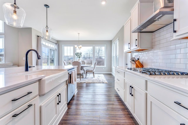 kitchen featuring a sink, dark wood-style floors, white cabinetry, appliances with stainless steel finishes, and wall chimney range hood