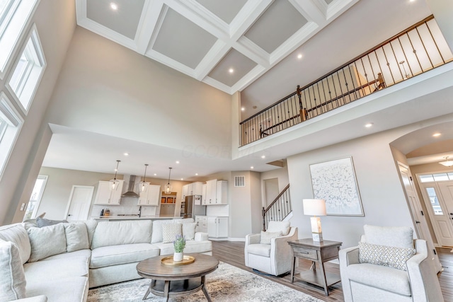 living room with visible vents, coffered ceiling, wood finished floors, and a towering ceiling