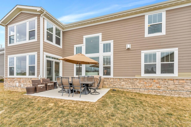 rear view of house with a yard, stone siding, and a patio area