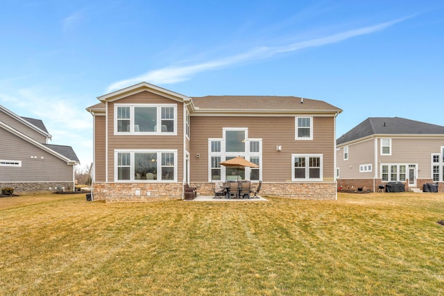 rear view of house with a patio area, stone siding, and a yard