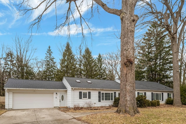 ranch-style house featuring driveway, an attached garage, and a shingled roof