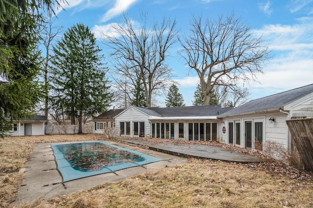 rear view of house with a patio area, fence, a covered pool, and a sunroom