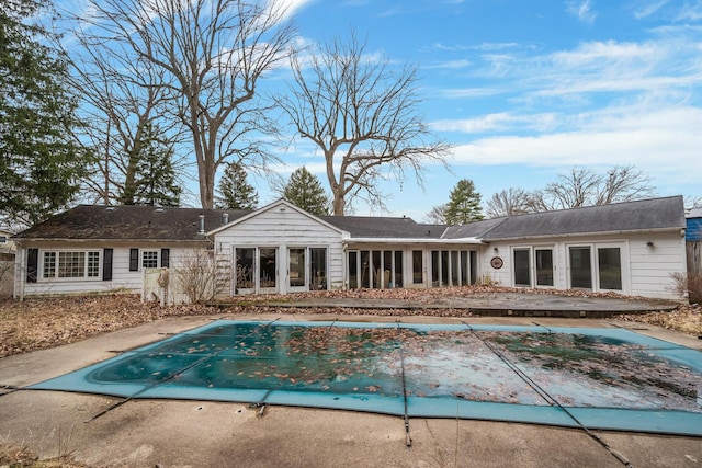 back of property featuring a covered pool, a sunroom, and a patio area