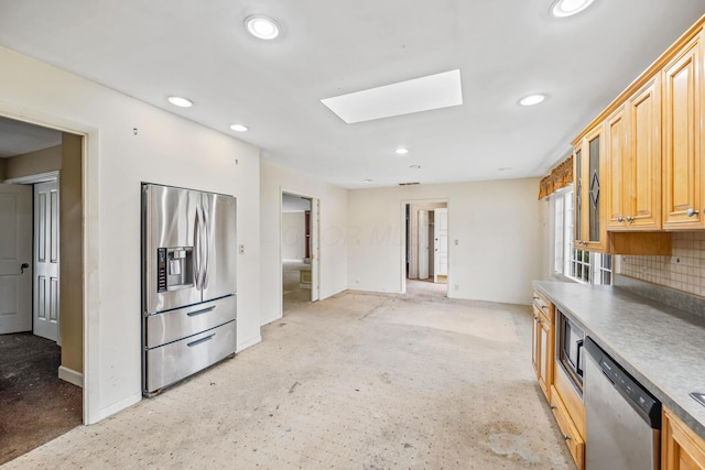 kitchen featuring baseboards, decorative backsplash, recessed lighting, a skylight, and stainless steel appliances