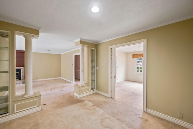 interior space featuring crown molding, baseboards, ornate columns, and carpet floors