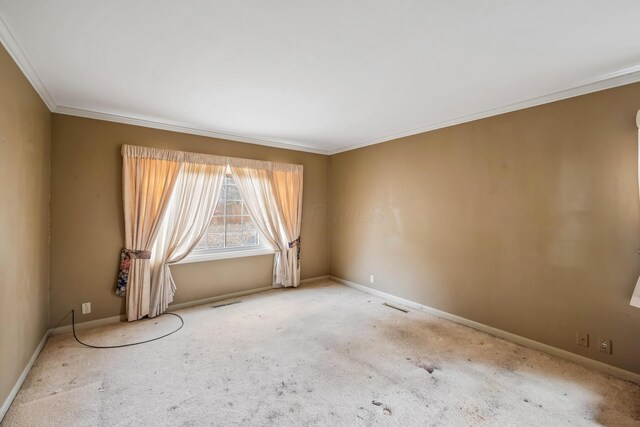 carpeted empty room featuring visible vents, crown molding, and baseboards