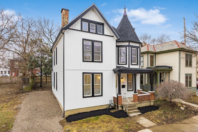 view of front of property with a porch, a chimney, and fence