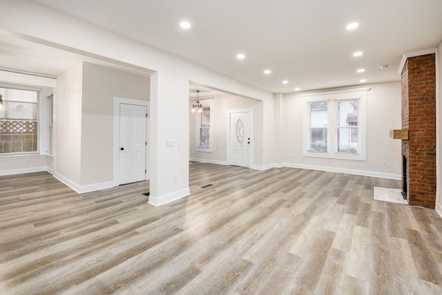 unfurnished living room with recessed lighting, a fireplace, baseboards, and light wood finished floors