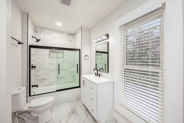 bathroom featuring marble finish floor, toilet, a healthy amount of sunlight, and shower / bath combination with glass door