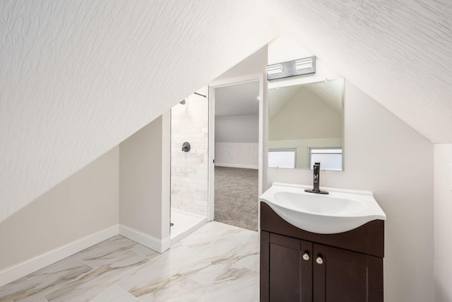 full bath with vanity, baseboards, lofted ceiling, a tile shower, and marble finish floor